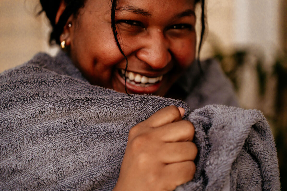 A member wrapped in a towel, laughing, right after a cold plunge