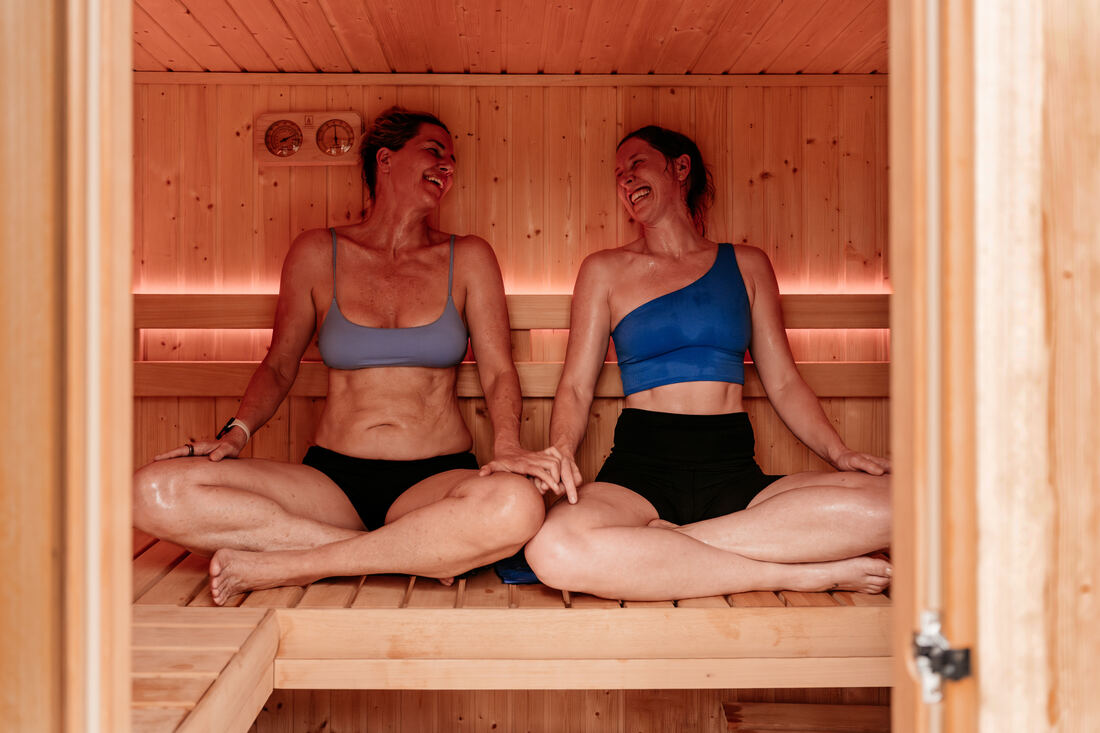 Two RITUAL members laughing together on the sauna bench